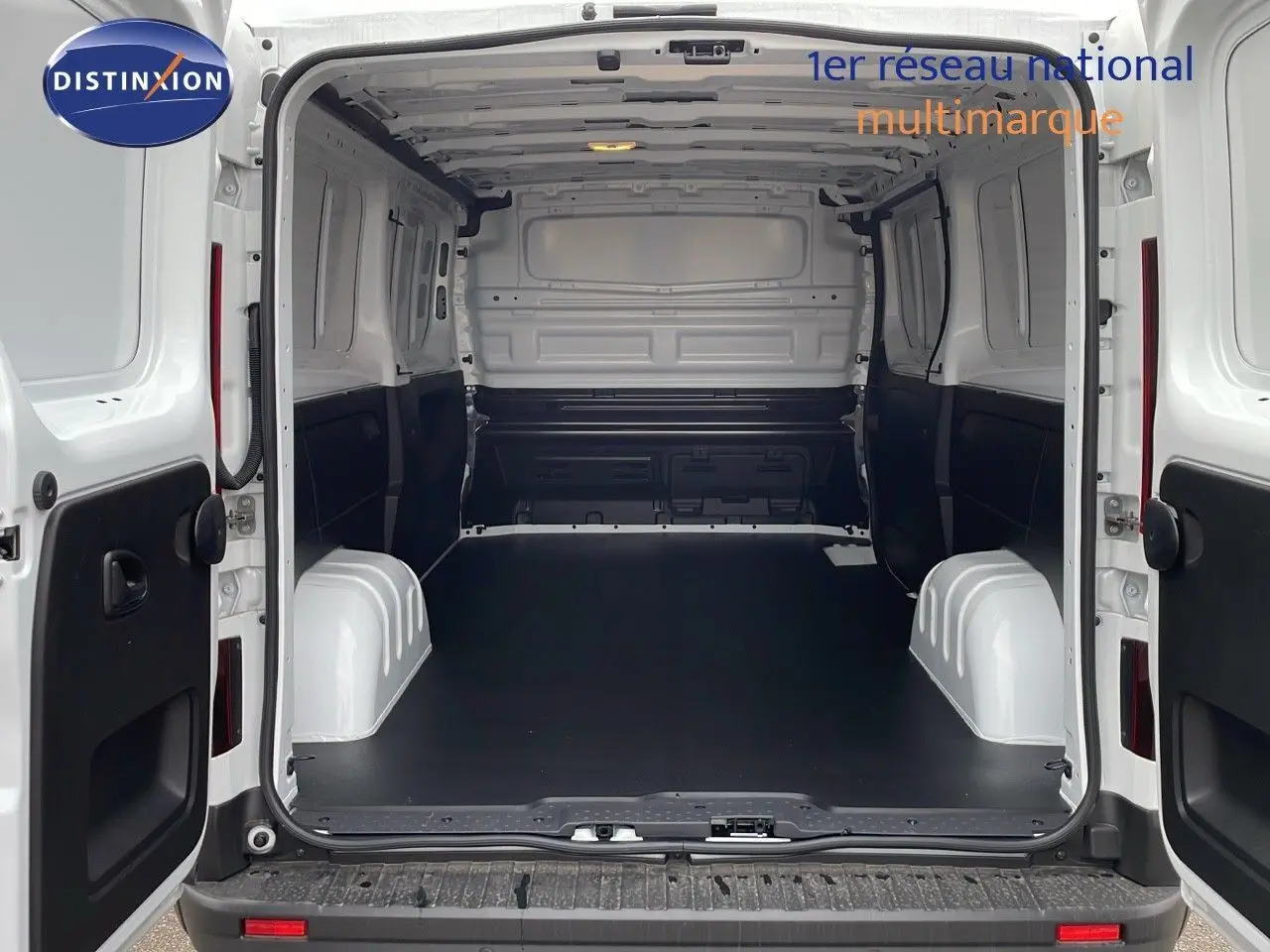 Vue arrière ouverte du Renault Trafic Fourgon blanc glacier montrant l'espace de chargement vide et les portes battantes ouvertes.