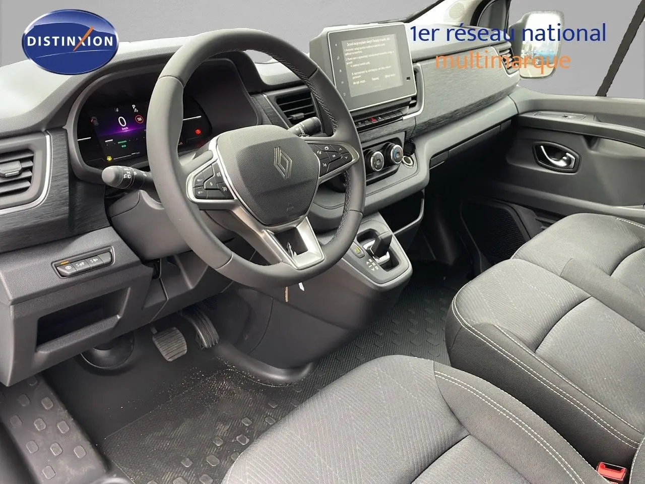 Vue intérieure côté conducteur du Renault Trafic Fourgon 2025 avec tableau de bord moderne et sièges tissu noir.