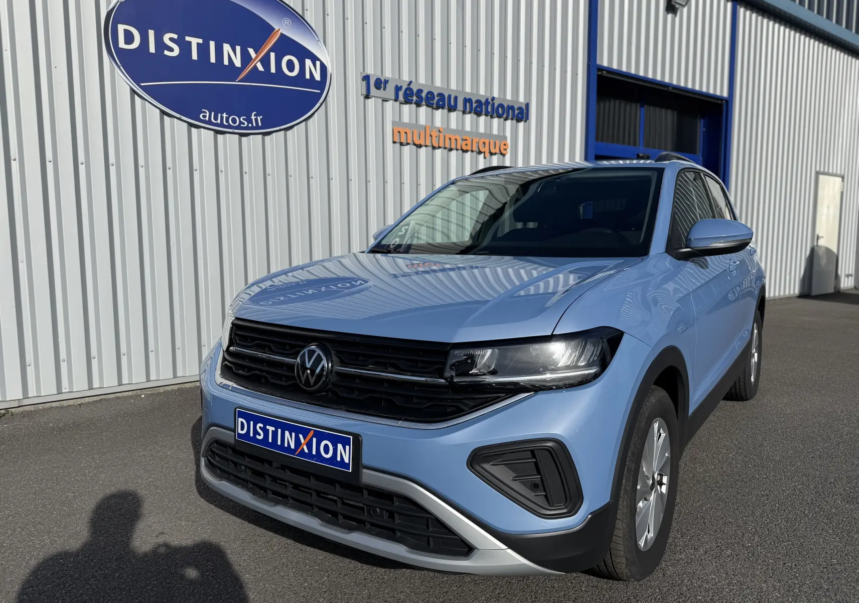 Vue 3/4 avant droite d'un Volkswagen T-Cross 2024 bleu Sky Metal avec feux LED et jantes alliage 16 pouces.