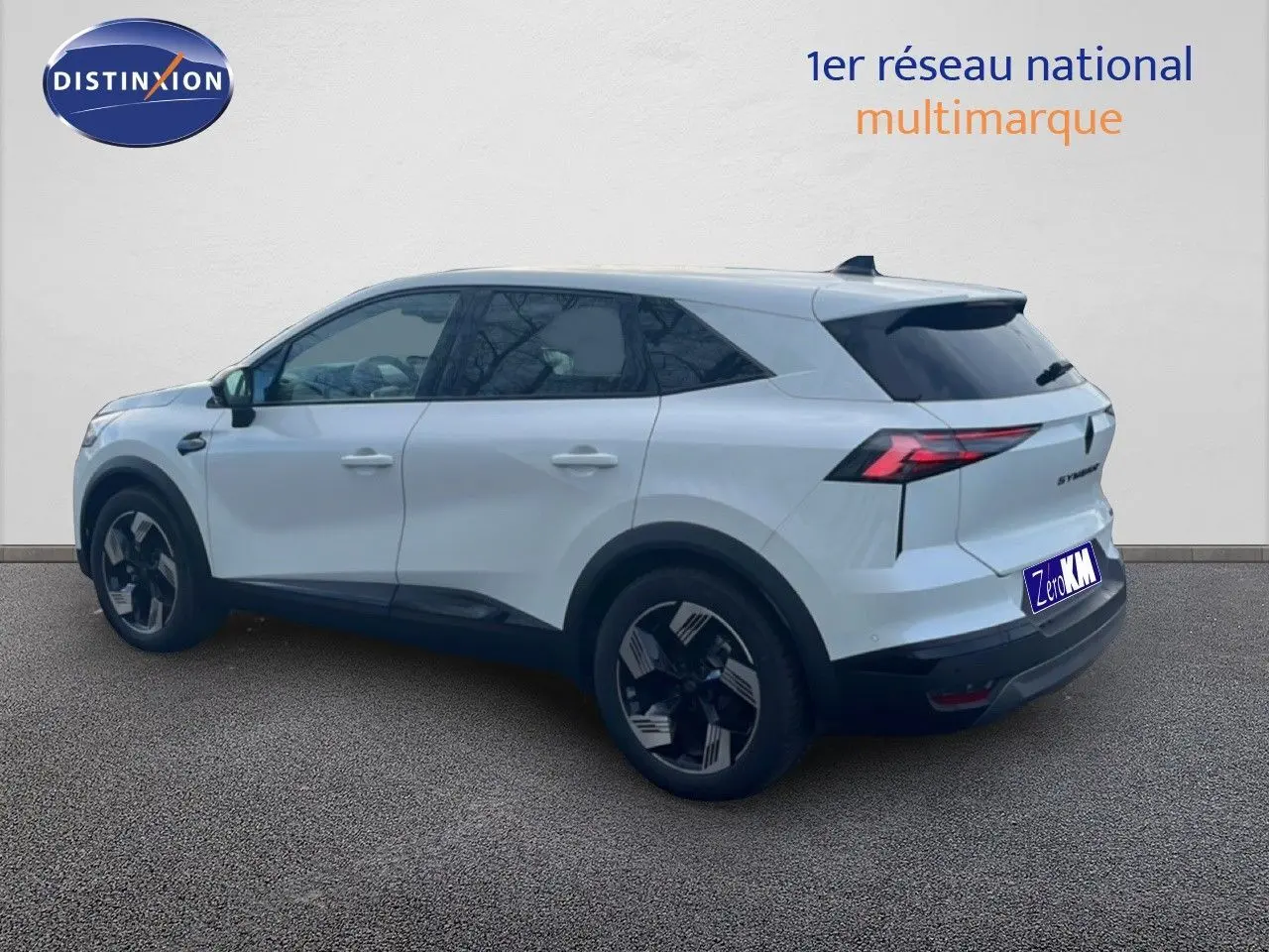 Renault Symbioz blanc nacré métal vu de 3/4 arrière droit, avec jantes noires et feux arrière LED distinctifs.