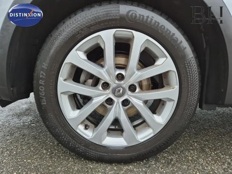 Gros plan sur la jante alu argentée avec logo Renault d'un Kadjar blanc, vue latérale roue avant droite.