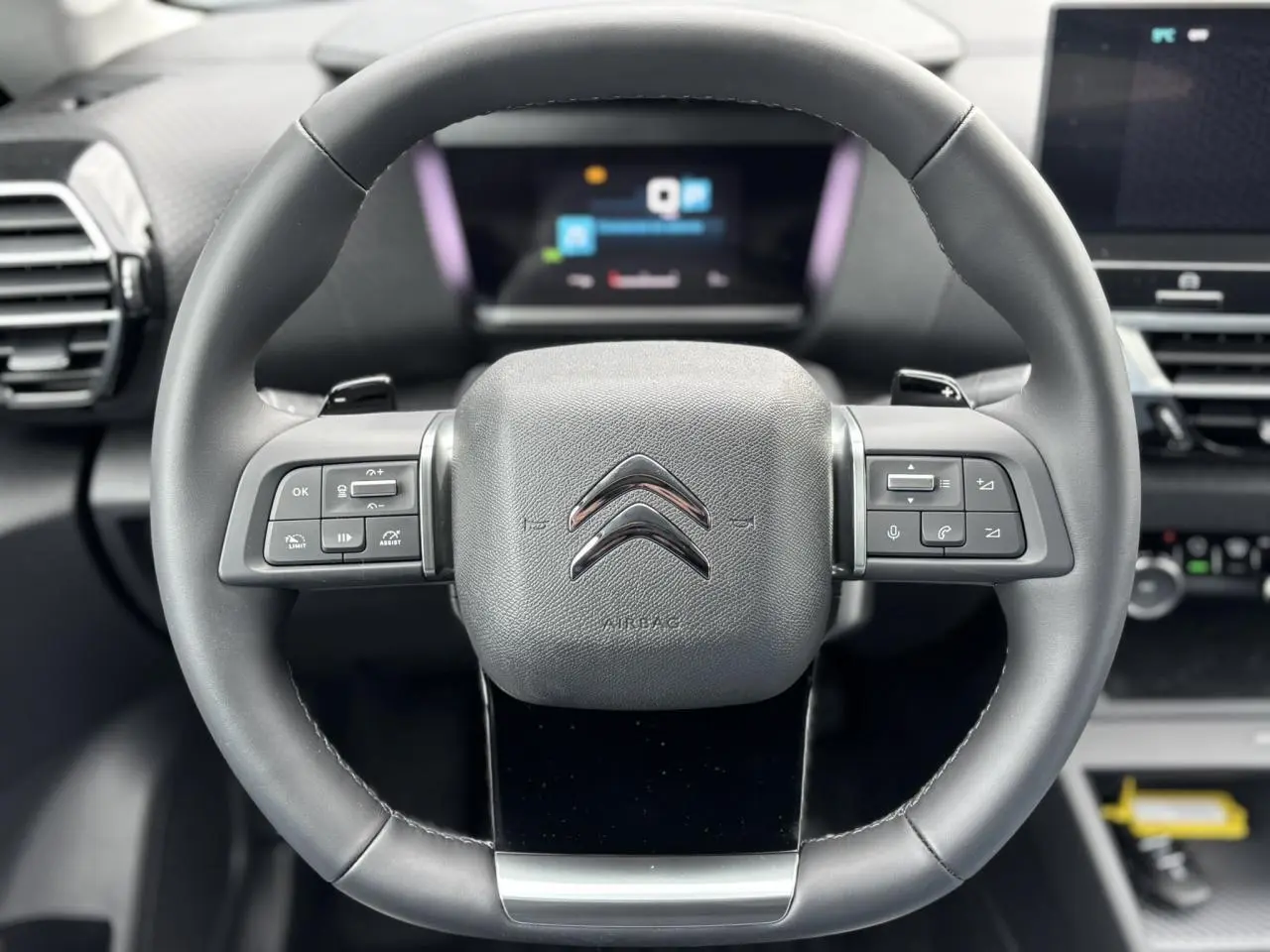 Volant cuir noir avec commandes intégrées du Citroën C4 PureTech 130 2024, intérieur moderne et écran numérique en arrière-plan.