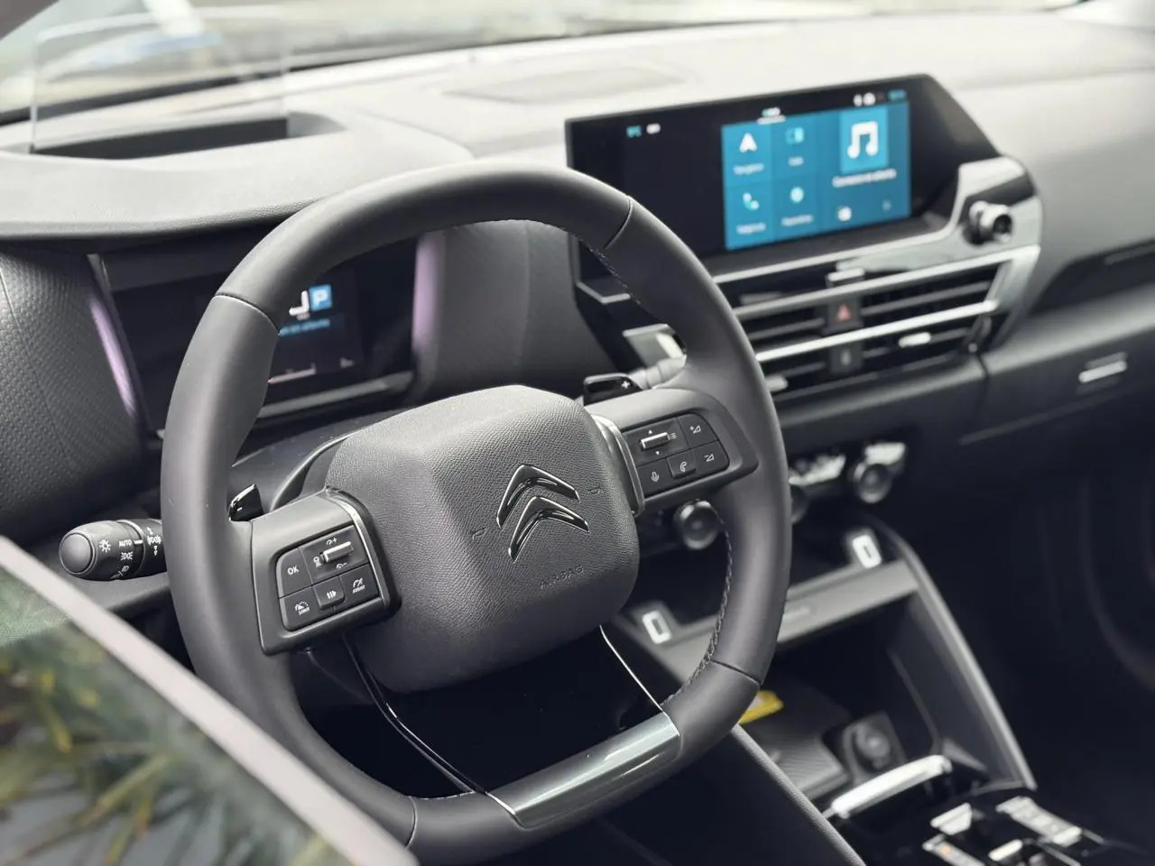 Vue intérieure centrée sur le volant cuir noir de la Citroën C4 2024 avec écran tactile et commandes au volant.