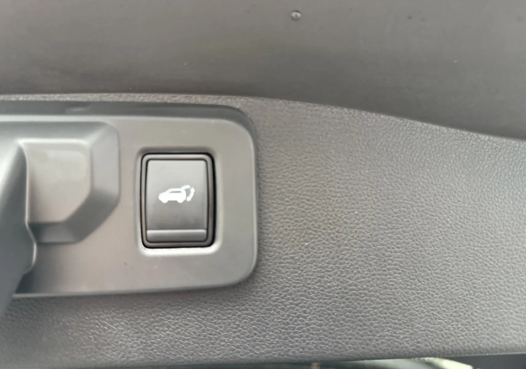 Bouton d'ouverture électrique du hayon sur le panneau intérieur d'un Renault Austral gris schiste toit noir.