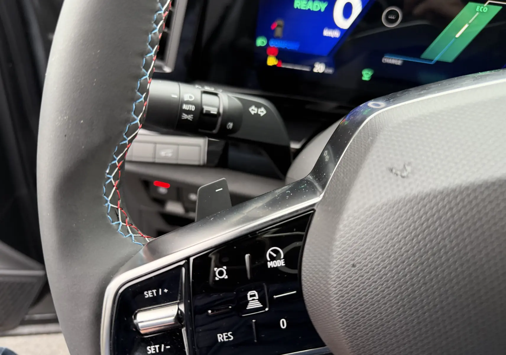 Gros plan sur le volant à gauche du Renault Austral 2025, avec surpiqûres tricolores et commandes intégrées.