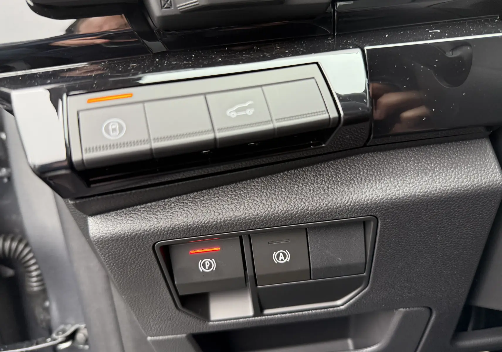 Gros plan sur les commandes du frein de stationnement et ouverture du coffre du Renault Austral 2025, intérieur noir.