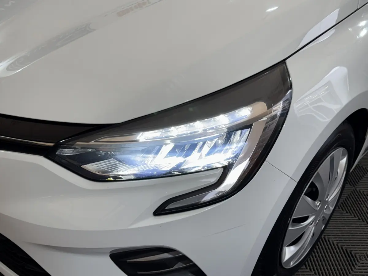 Gros plan sur l'avant droit blanc de la Renault Clio 2020 avec phares LED allumés et jante visible.