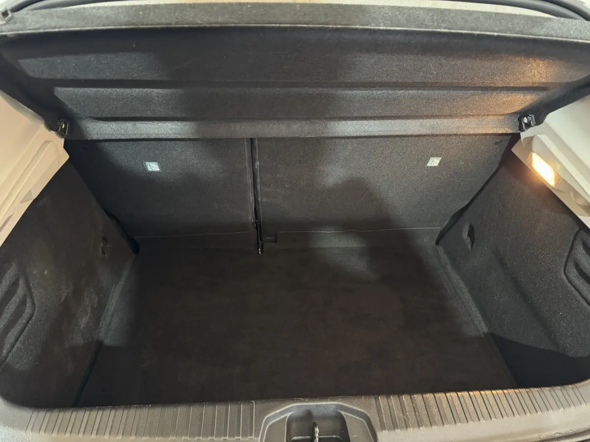 Vue intérieure du coffre noir ouvert d'une Renault Clio Business TCe 100 blanche de 2020, sans chargement visible.