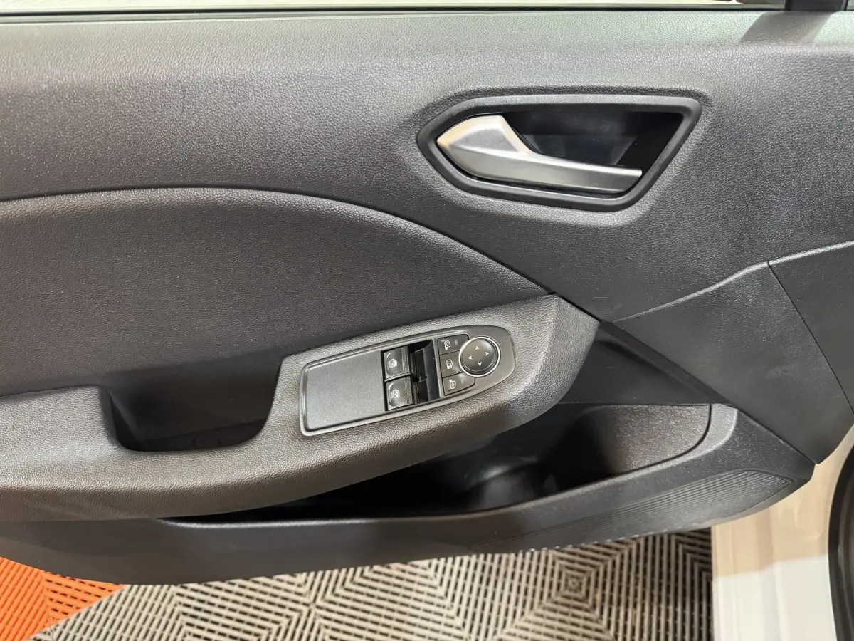 Vue rapprochée de la porte avant gauche noire de la Renault Clio Business TCe 100 blanche avec commandes électriques.