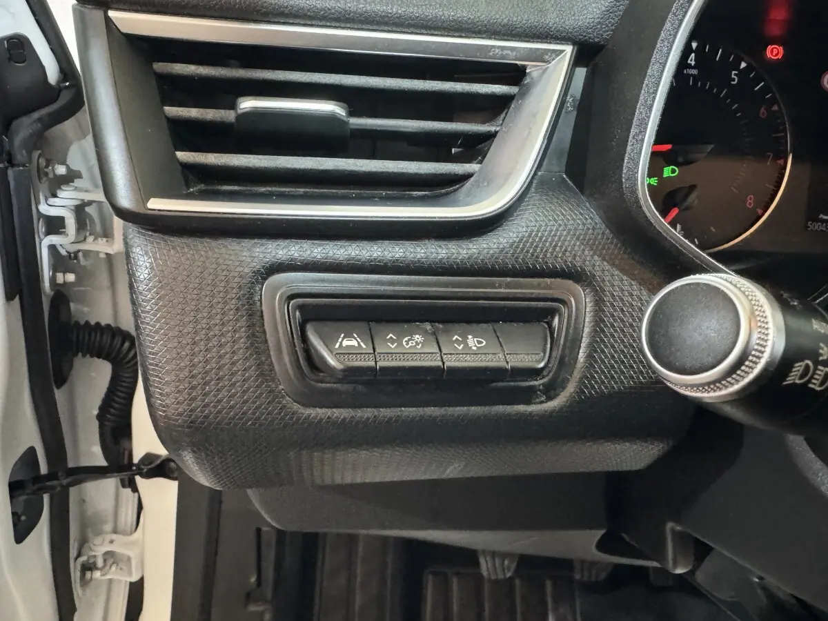 Gros plan sur les commandes d’assistance et réglage des phares du tableau de bord côté gauche d’une Renault Clio Business blanche 2020.