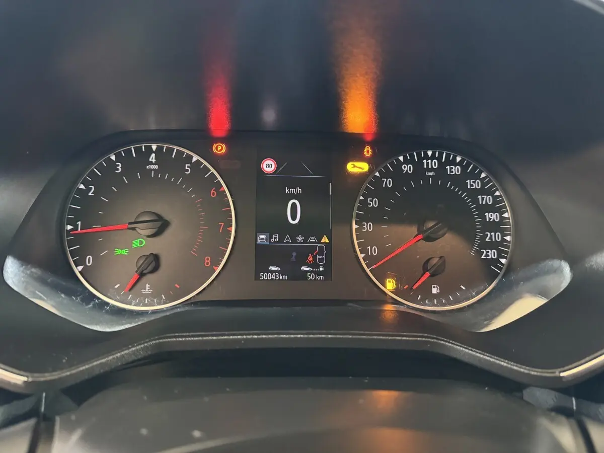 Vue rapprochée du tableau de bord de la Renault Clio Business blanc, affichage digital et compteurs analogiques allumés.