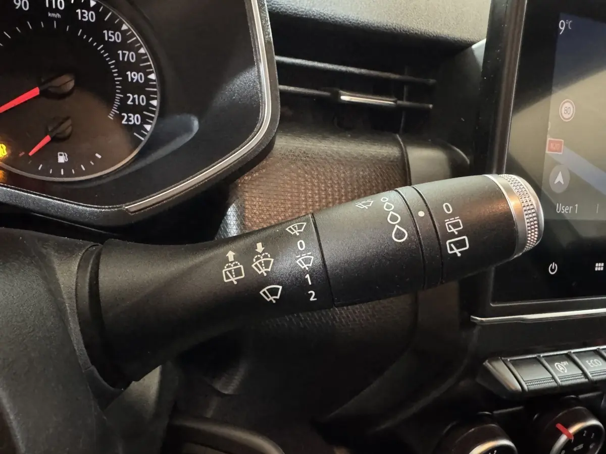 Gros plan sur la commande des essuie-glaces à gauche du tableau de bord noir de la Renault Clio Business TCe 100 blanche de 2020.