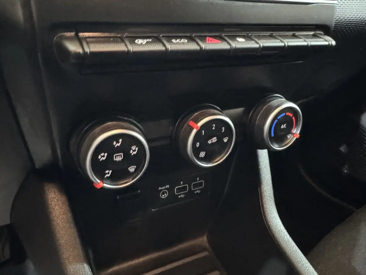 Gros plan sur les commandes de climatisation et ventilation noires du tableau de bord de la Renault Clio Business blanche de 2020.