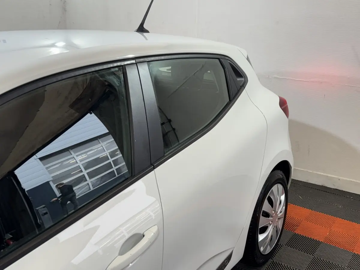 Vue arrière côté droit d'une Renault Clio blanche Business TCe 100, avec poignées de porte intégrées et jantes acier.