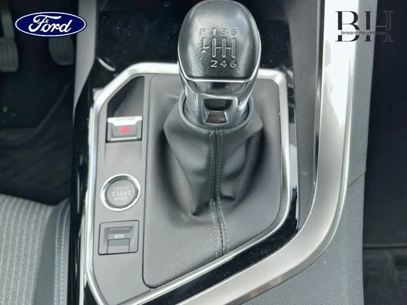 Levier de vitesses manuel en cuir noir vu de dessus dans l'habitacle d'un Peugeot 5008 noir, avec bouton démarrage et mode Eco.
