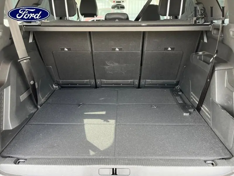 Coffre ouvert vu de l'arrière d'un Peugeot 5008 noir Perla Nera, montrant la banquette arrière rabattue et un intérieur spacieux.