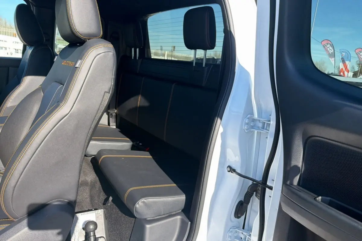 Vue intérieure côté droit du Ford Ranger blanc 2025, montrant les sièges arrière en tissu noir avec surpiqûres orange.