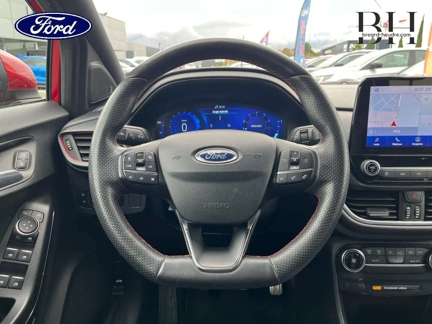 Vue intérieure centrée sur le volant cuir perforé et l'écran tactile du Ford Puma rouge Premium Lucid 2020.