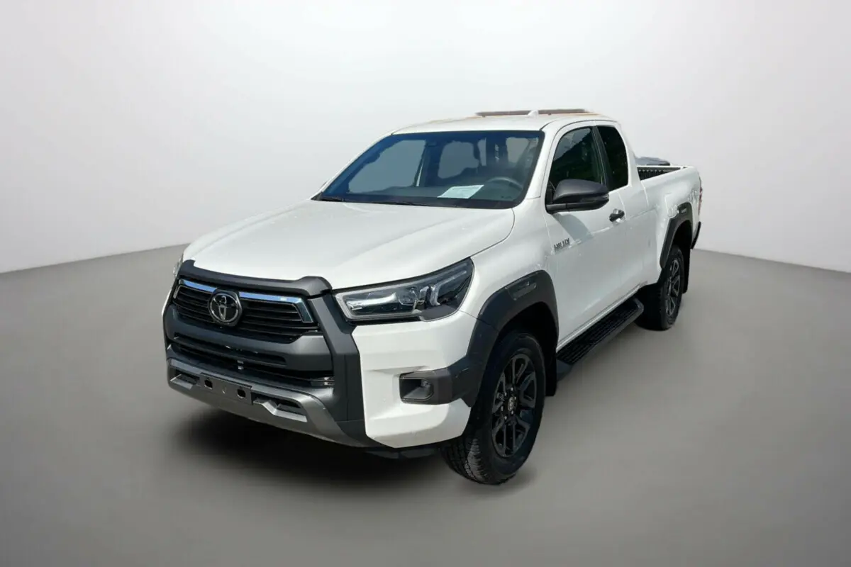 Toyota Hilux 2025 blanc pur en 3/4 avant droit, avec calandre noire et jantes noires distinctives.