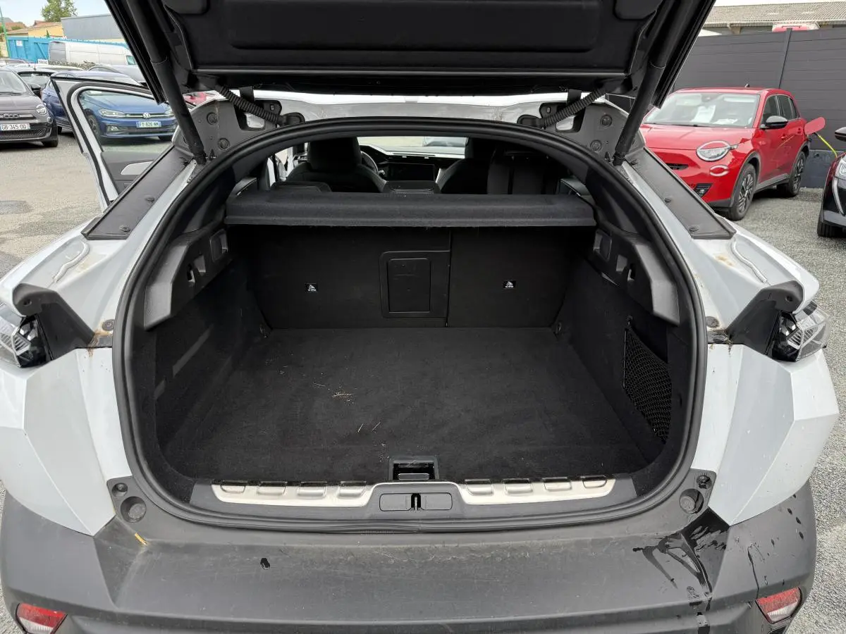 Coffre ouvert vu de l'arrière d'une Peugeot 408 blanche, montrant l'espace de chargement vide et la plage arrière.