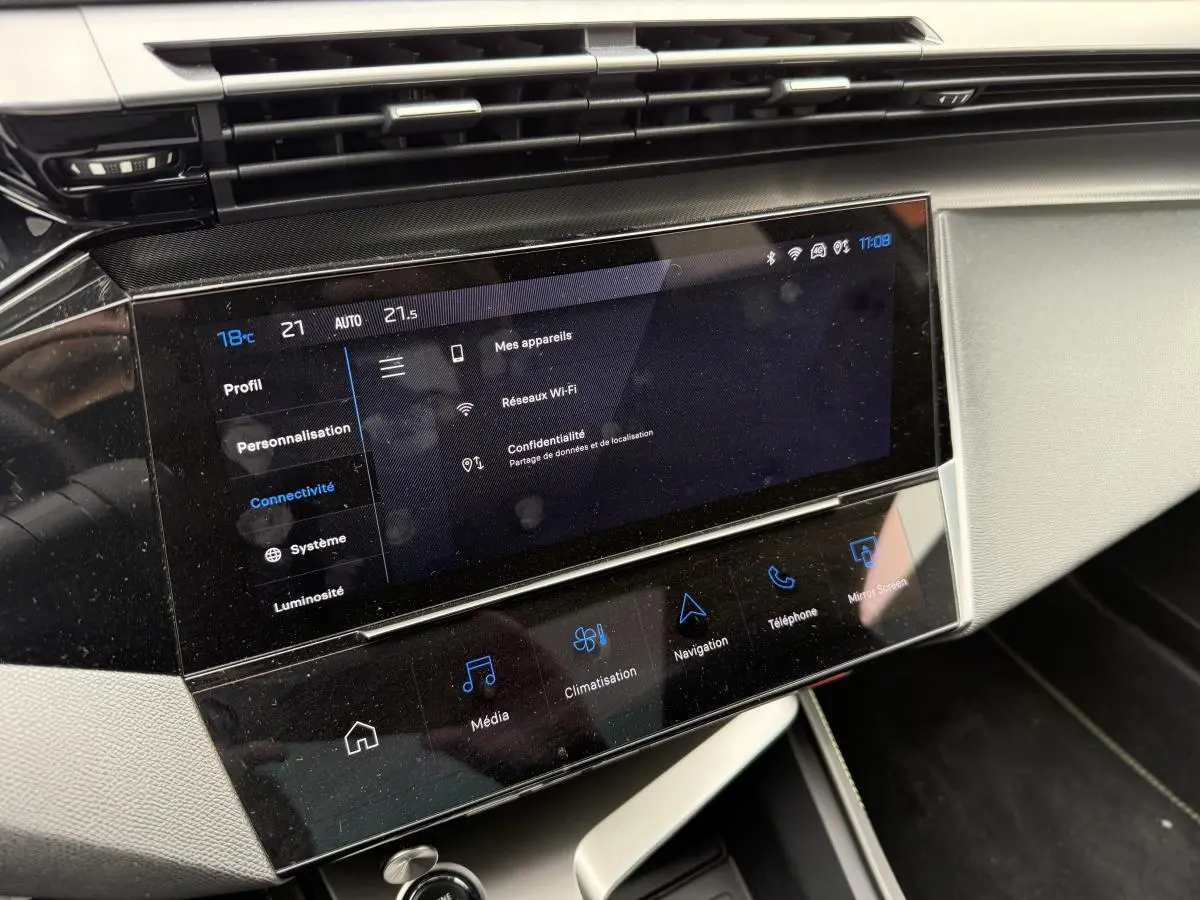 Écran tactile central 10'' du tableau de bord de la Peugeot 408 blanche, affichant les réglages de connectivité.
