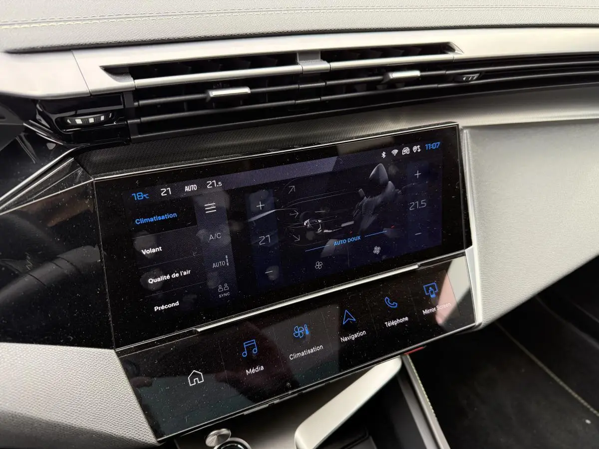 Écran tactile central de la console avant de la Peugeot 408 blanche, affichant les réglages de climatisation.