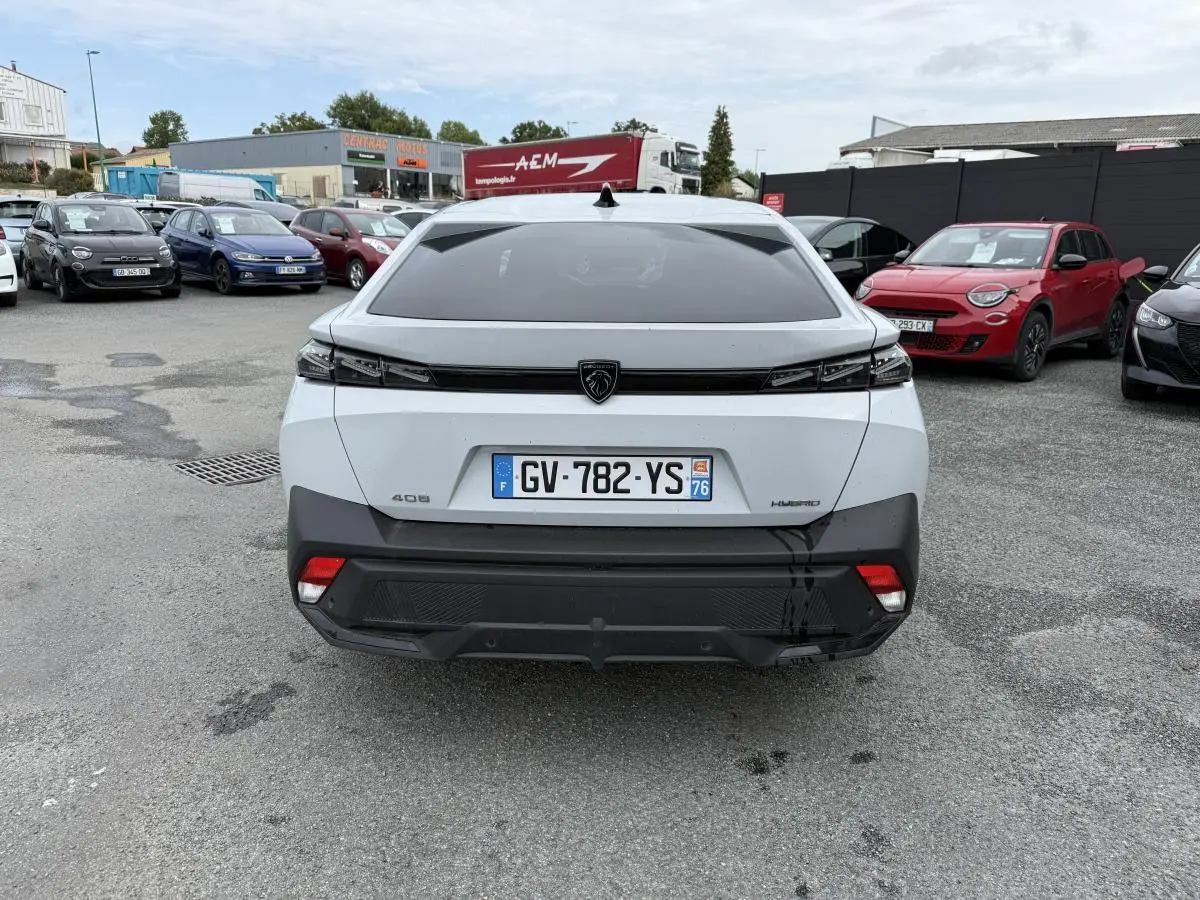 Vue arrière d'une Peugeot 408 blanche hybride avec feux arrière noirs et plaque d'immatriculation française.