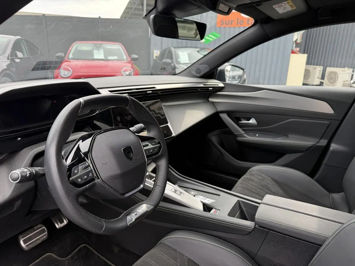 Intérieur de la Peugeot 408 blanc, vue côté conducteur sur le volant GT et la console centrale moderne.