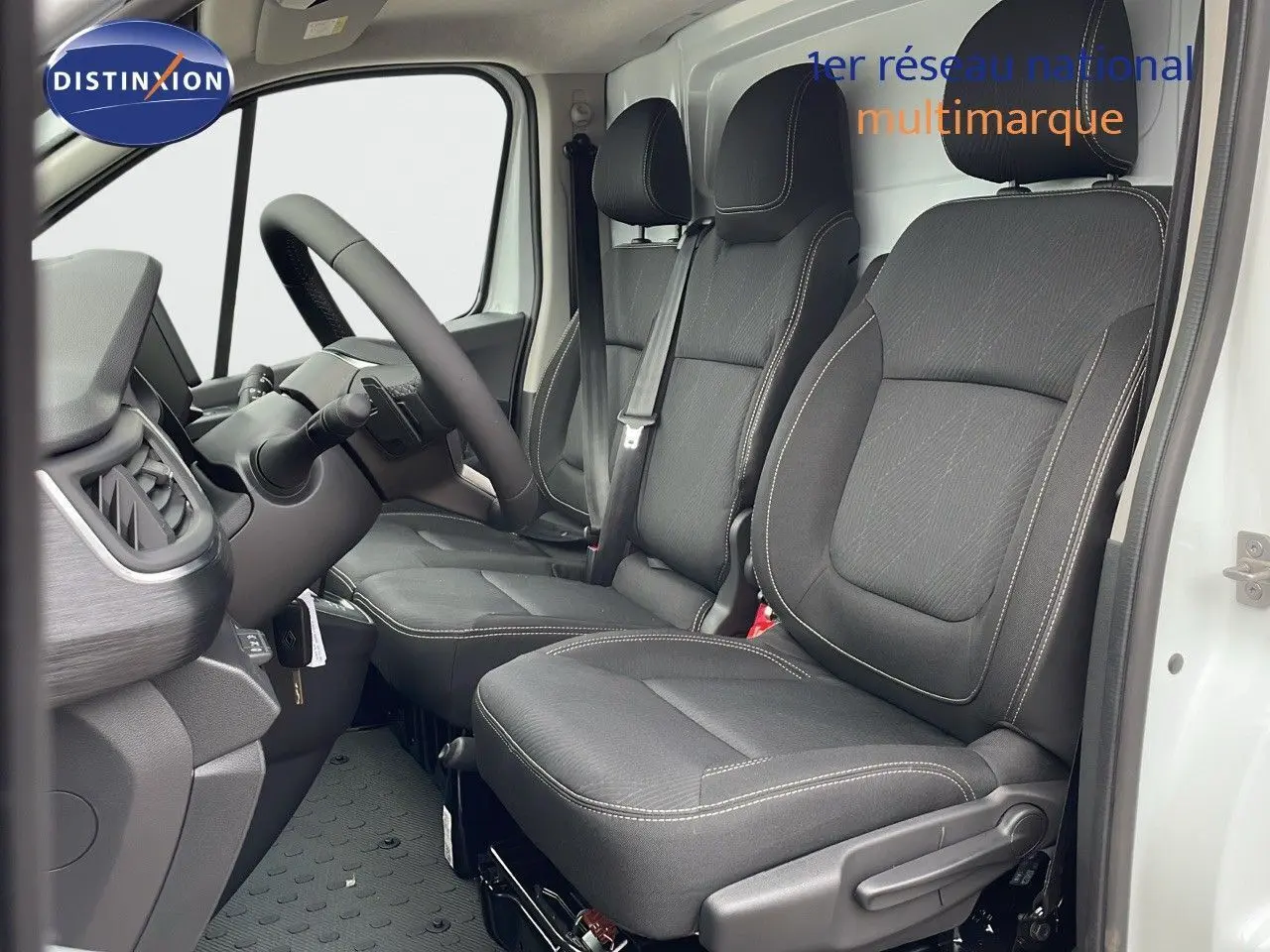 Vue intérieure côté conducteur du Renault Trafic Fourgon blanc glacier 2025, sièges noirs avec surpiqûres claires.