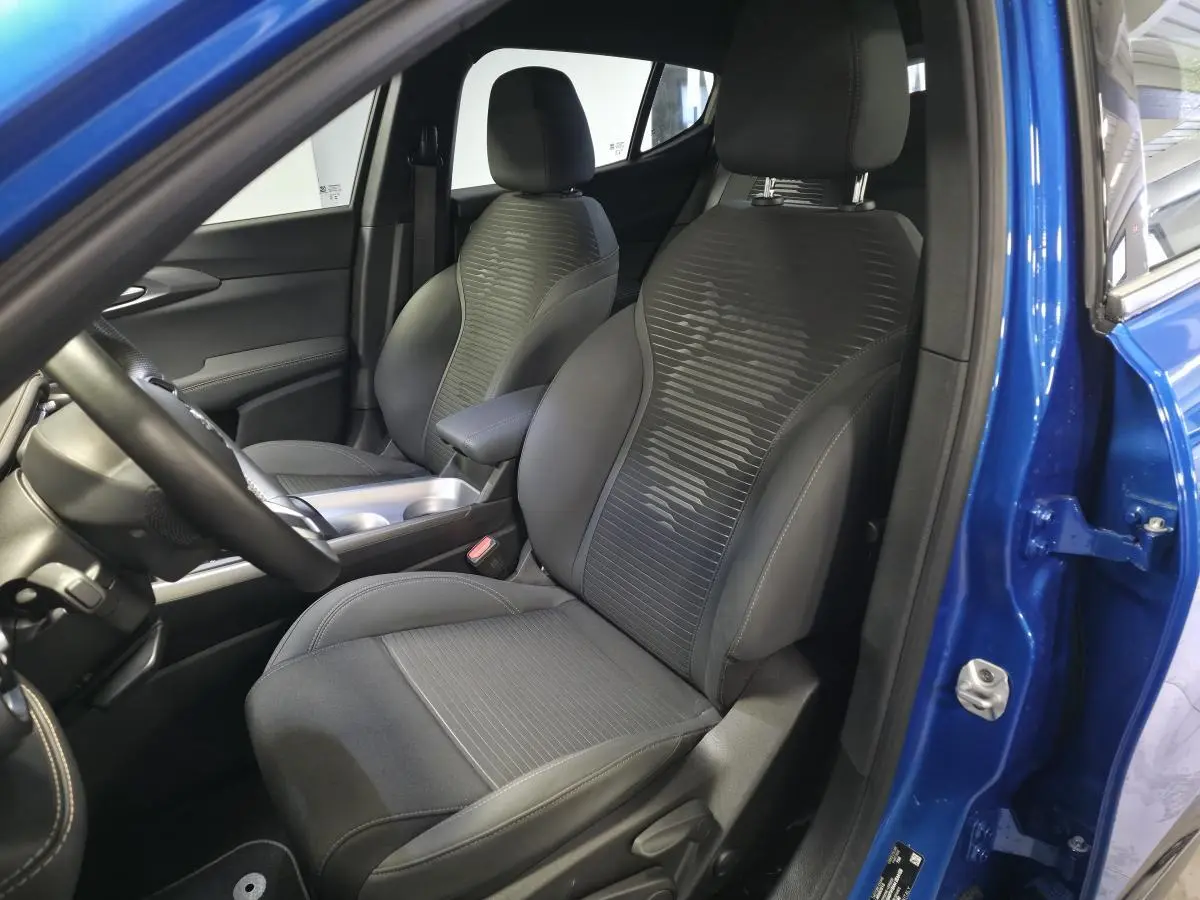 Vue intérieure côté conducteur de l'Alfa Romeo Tonale 2025 bleu, sièges tissu noir avec surpiqûres beige et volant cuir.