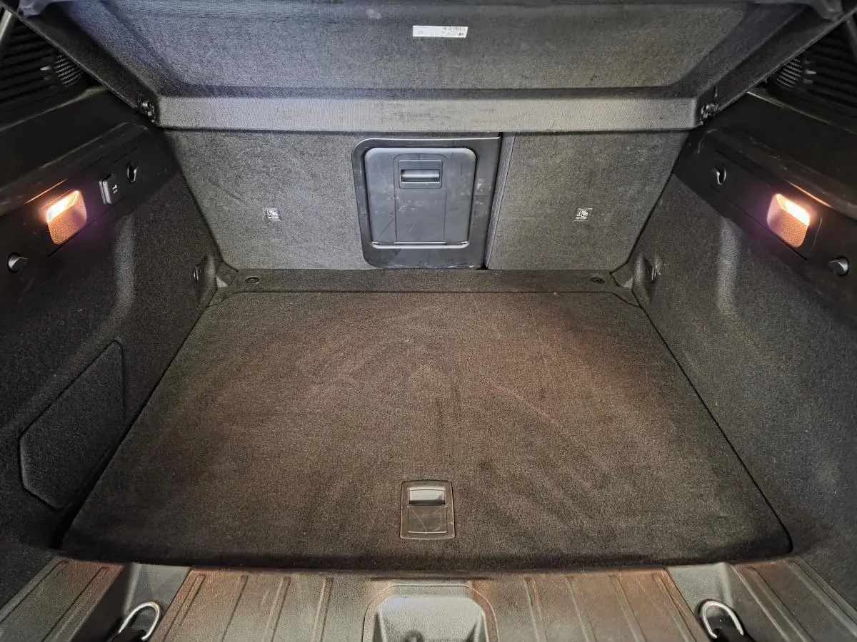 Coffre ouvert de l'Alfa Romeo Tonale 2025, vue intérieure montrant le tapis noir et l'éclairage latéral.