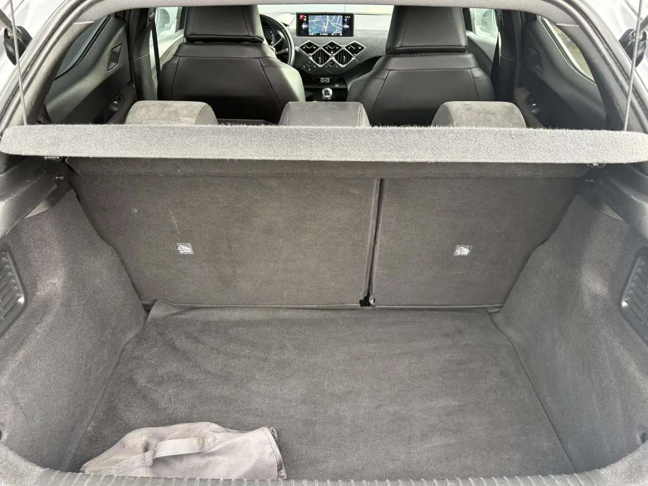 Vue intérieure du coffre et des sièges avant noirs du DS3 Crossback gris Artense, avec tableau de bord et écran GPS visibles.