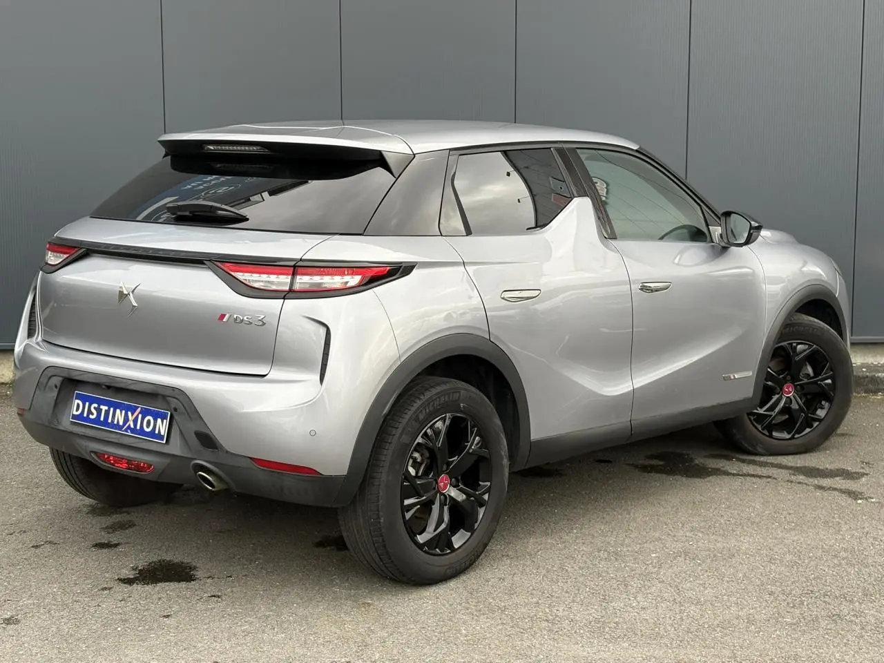 DS3 Crossback gris Artense vu en 3/4 arrière droit, avec jantes alliage noires et feux arrière LED distinctifs.