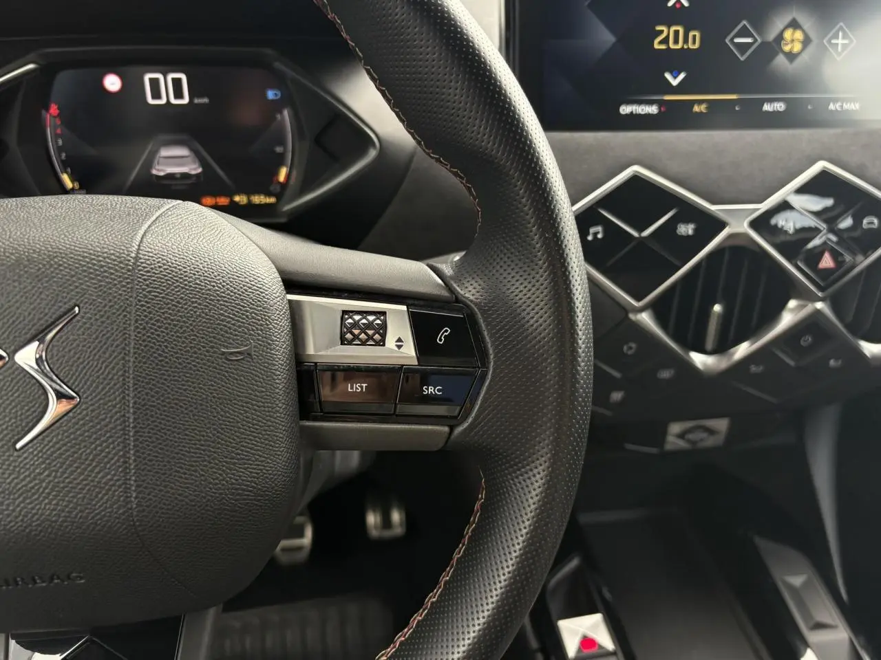 Gros plan sur le volant cuir perforé et les commandes multifonctions du tableau de bord numérique du DS3 Crossback 2021.