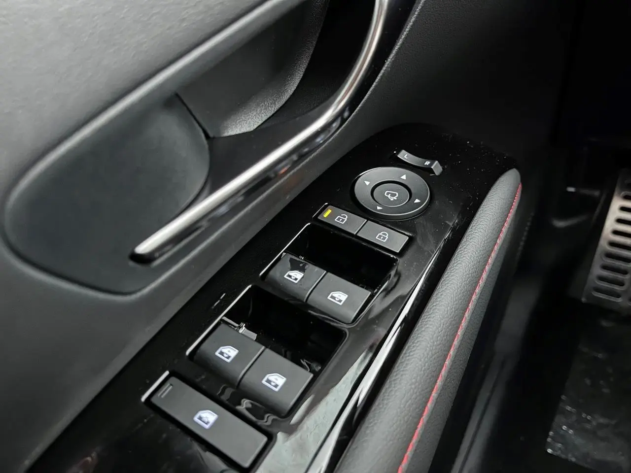 Gros plan sur la commande des vitres et rétroviseurs côté conducteur du Hyundai Tucson 2025 en finition N-Line, intérieur noir avec surpiqûres rouges.