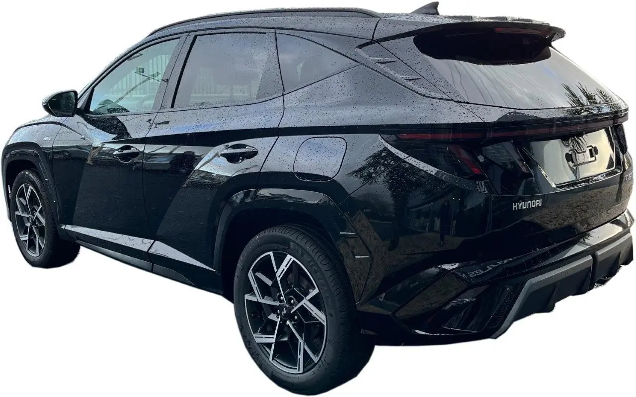 Vue 3/4 arrière droite du Hyundai Tucson 2025 hybride en noir Abyss, avec jantes alliage et feux arrière LED continus.
