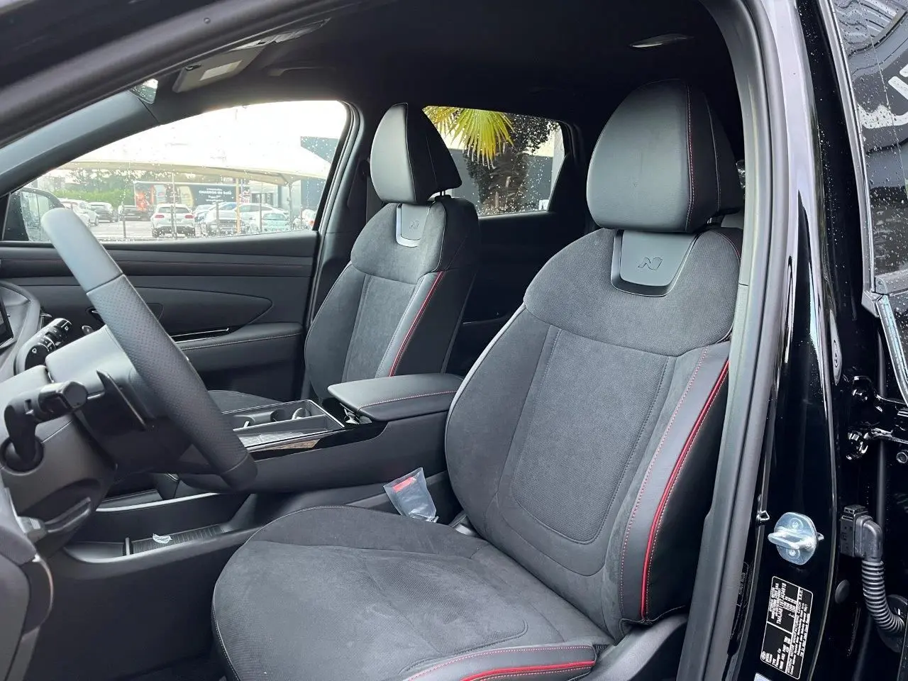 Vue intérieure côté conducteur du Hyundai Tucson 2025 noir Abyss, sièges en cuir et alcantara avec surpiqûres rouges et logo N.