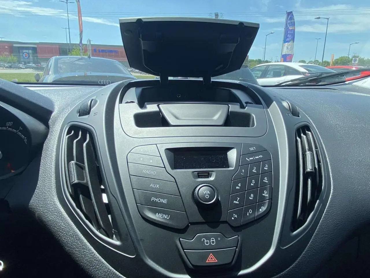 Vue rapprochée du tableau de bord noir du Ford Tourneo Courier 2022 avec commandes radio et rangement ouvert.