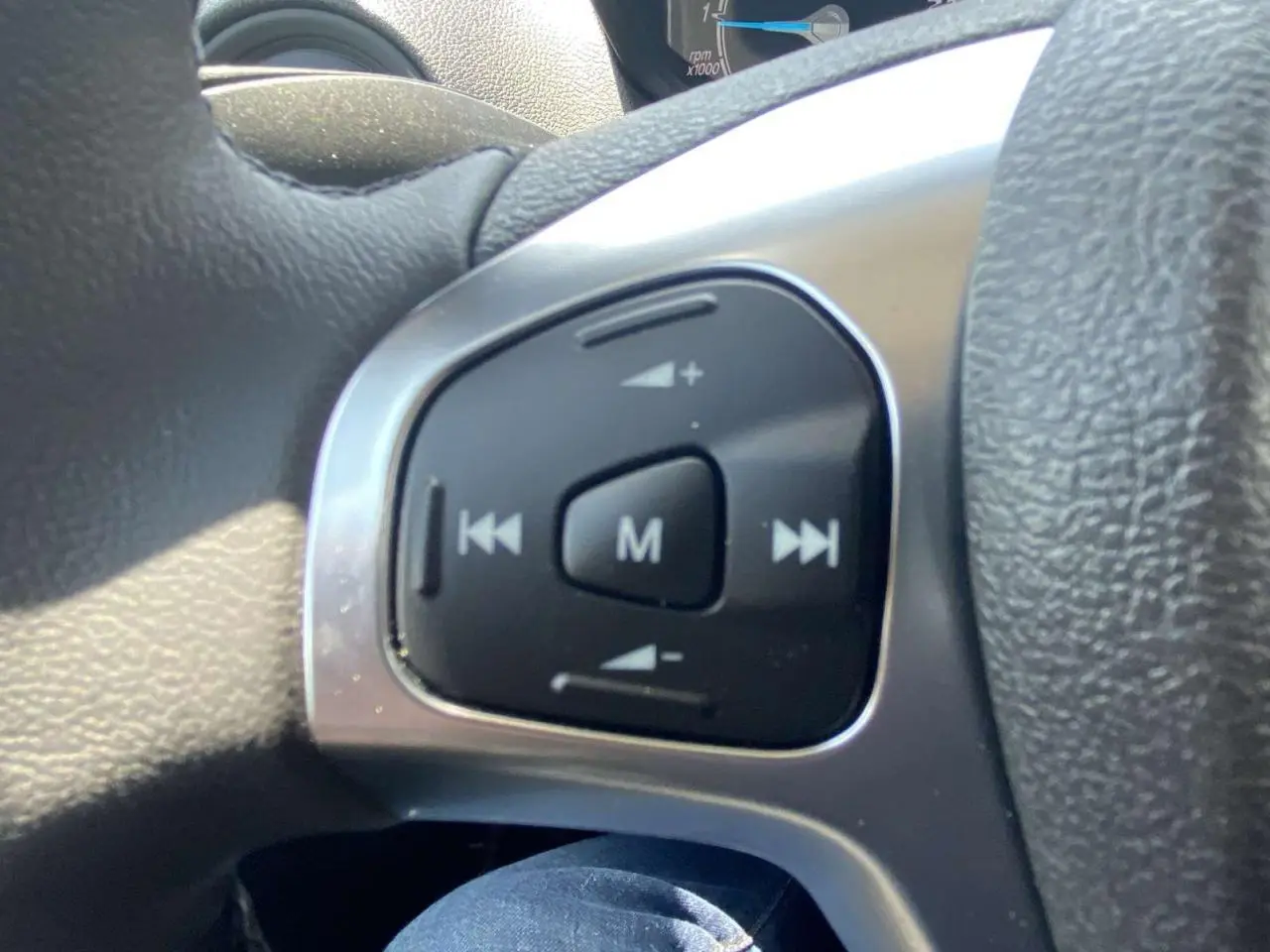 Gros plan sur les commandes audio au volant cuir noir du Ford Tourneo Courier blanc, version Trend 2022.