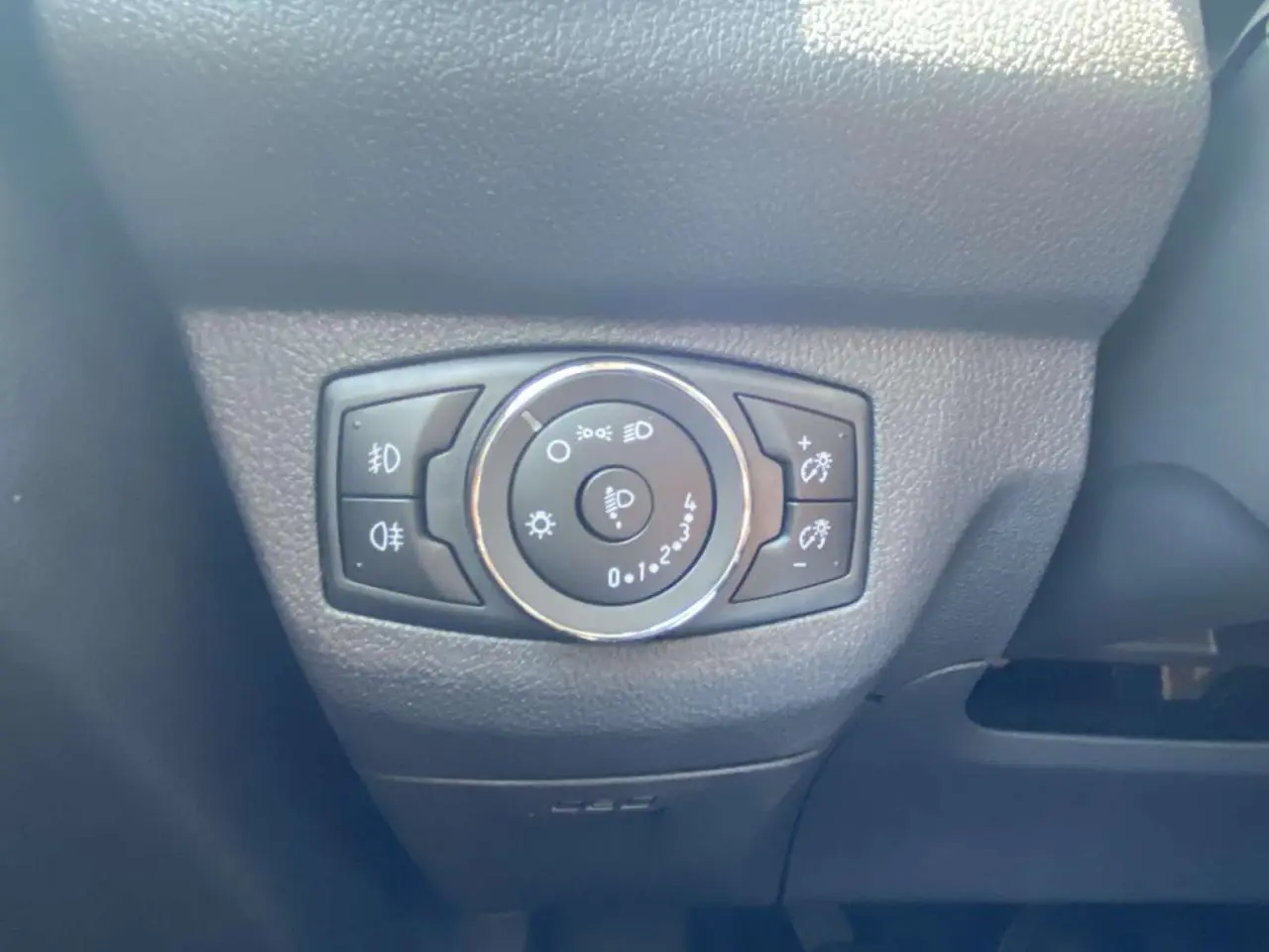 Gros plan sur le bouton de réglage des phares du Ford Tourneo Courier 2022, intérieur noir texturé.
