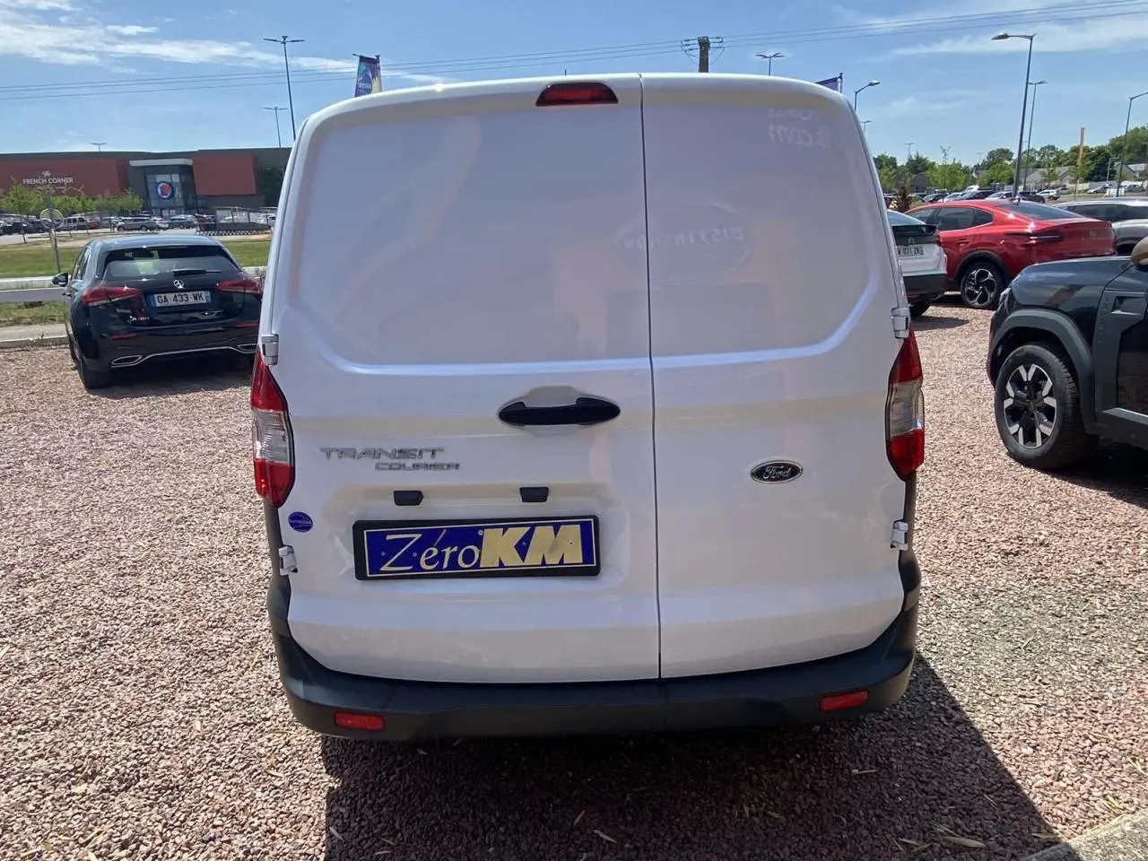 Vue arrière d’un fourgon blanc Ford Tourneo Courier 2022 avec portes battantes tôlées et plaque « Zéro KM » visible.