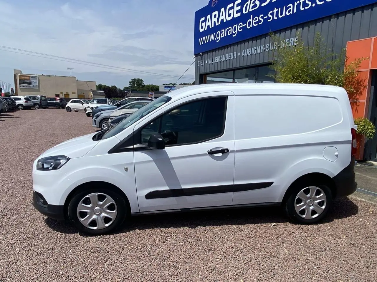 Fourgon blanc Ford Tourneo Courier 2022 vu de profil côté gauche, avec porte latérale coulissante et enjoliveurs cache moyeu.
