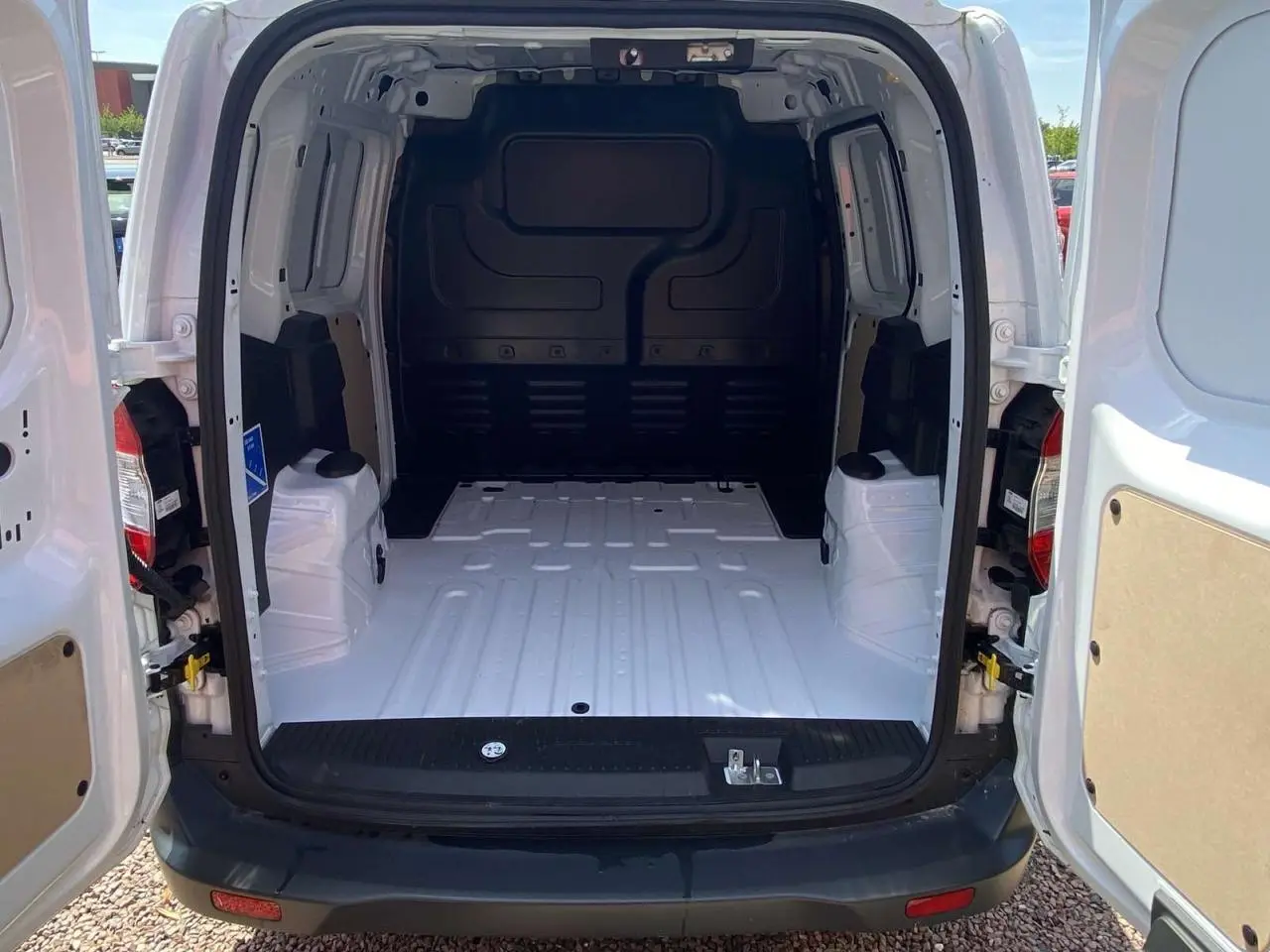Vue arrière du fourgon Ford Tourneo Courier blanc 2022 avec portes battantes ouvertes et espace de chargement vide.