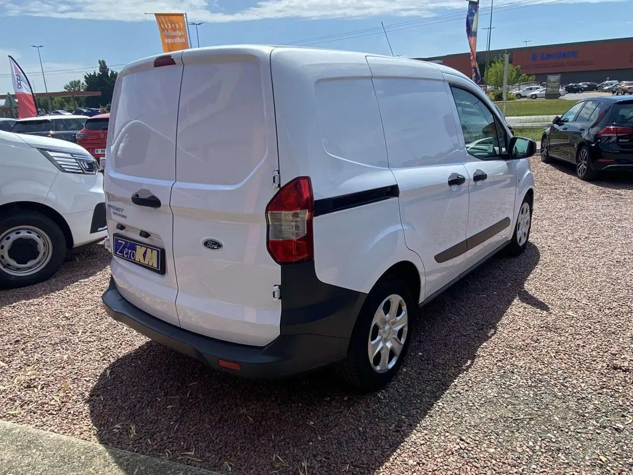 Vue 3/4 arrière droite d’un Ford Tourneo Courier blanc 2022 avec portes arrière battantes tôlées et porte latérale coulissante.