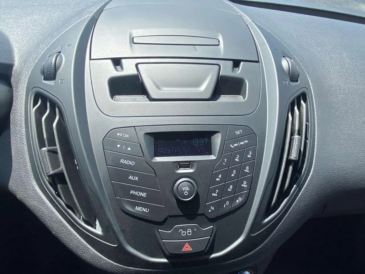 Vue rapprochée du tableau de bord noir du Ford Tourneo Courier 2022, avec commandes radio et ventilation centrales.