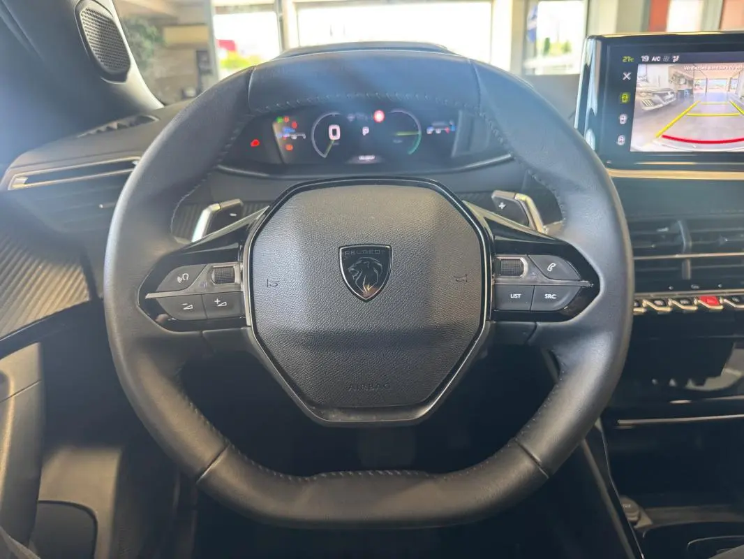 Vue intérieure centrée sur le volant cuir du Peugeot 2008 Hybrid 145 Allure avec cockpit numérique et écran tactile.