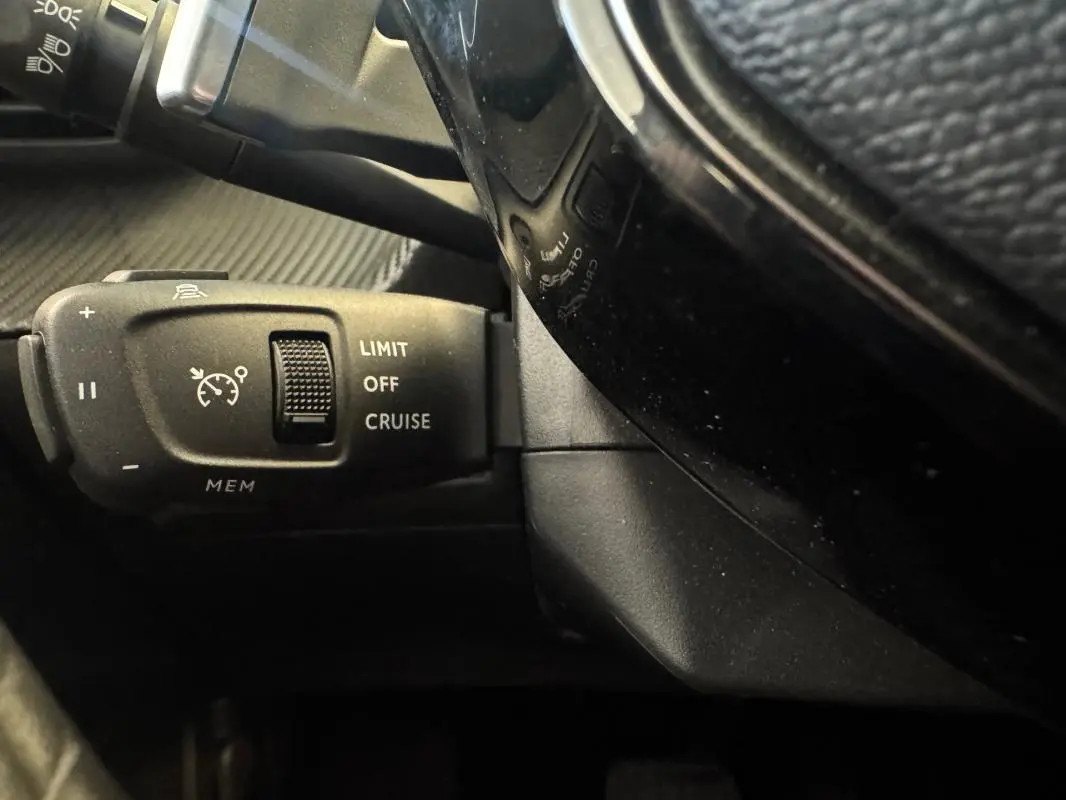 Gros plan sur la commande de régulateur de vitesse à gauche du volant du Peugeot 2008 Hybrid 145 e-DCS6 Allure gris.