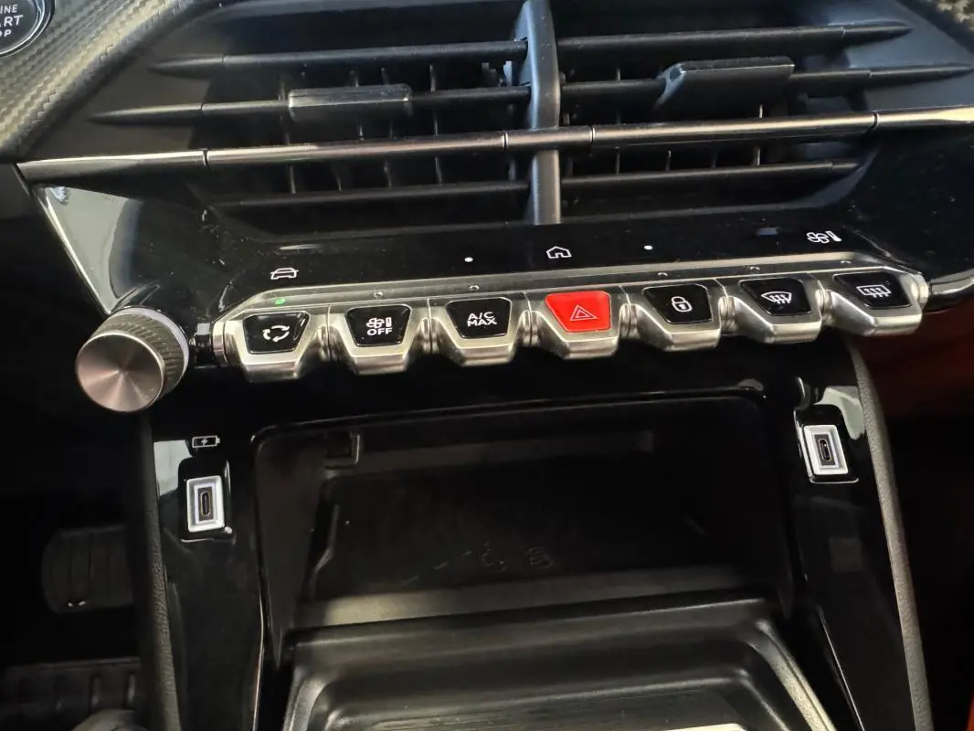 Vue rapprochée du tableau de bord du Peugeot 2008 Hybrid 145 Allure, montrant les commandes de climatisation et les ports USB.