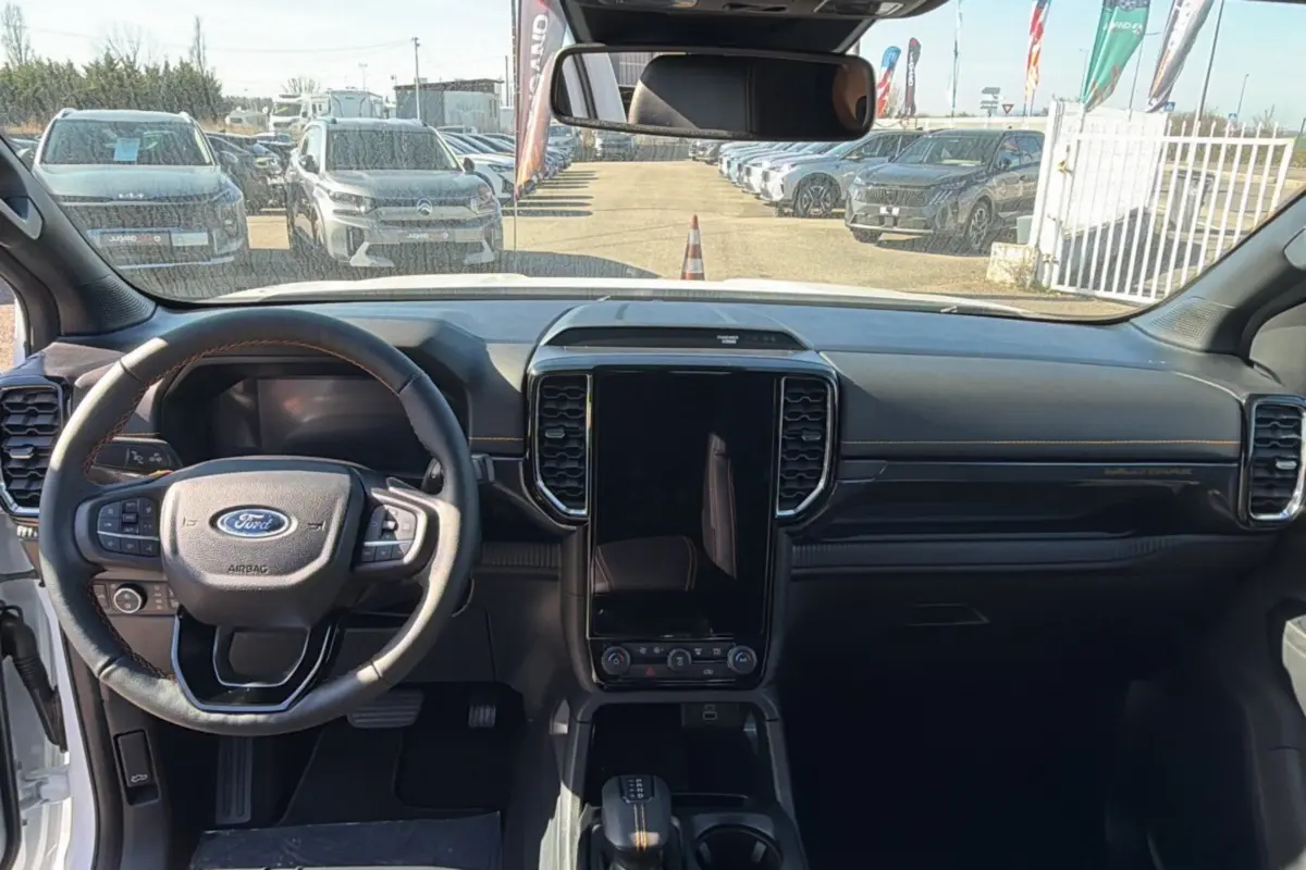 Vue intérieure frontale du Ford Ranger Wildtrak 2025 blanc, avec volant cuir multifonctions et écran tactile vertical.