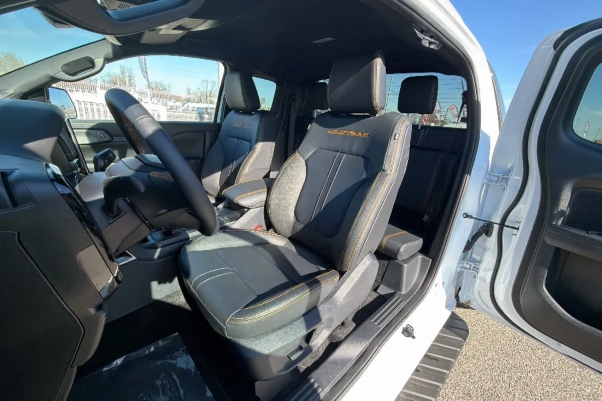 Intérieur du Ford Ranger Wildtrak 2025 blanc, vue côté gauche sur les sièges avant en cuir noir avec surpiqûres orange.